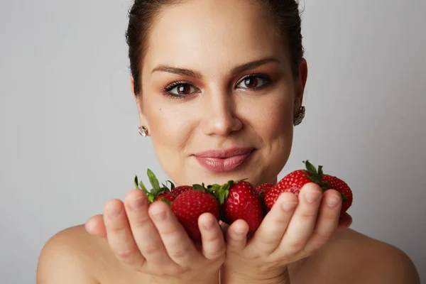 Pretty happy smiling girl with many strawberry over colorful white background.Portrait of brunette cutie with bowl of juicy strawberries — Stock Photo, Image