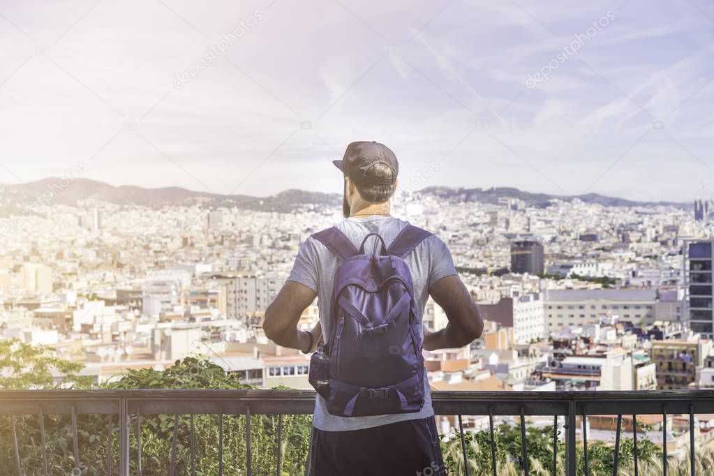 Traveler man looking on a big city, travel and active lifestyle concept.Bearded Tourist Man with backpack enjoy beautiful panoramic view of modern european city. Flare.