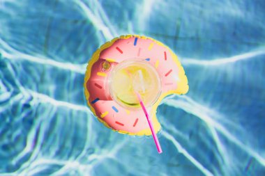 Taze kokteyl buz ve lezzetli limon bir şişme oyuncak pembe çörek oyuncak yüzme havuzunda yüzen ile. Tatil ve dinlenme zamanında yaz günü havuzda yüzmek.