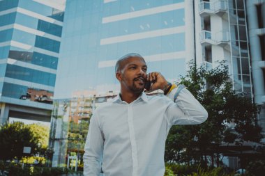 Pozitif Afro-Amerikan erkek Smartphone açık kullanarak. Office gökdelenler içinde belgili tanımlık geçmiş.