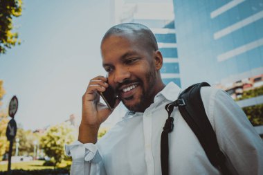 Pozitif Afro-Amerikan erkek Smartphone açık kullanarak. Office gökdelenler içinde belgili tanımlık geçmiş.