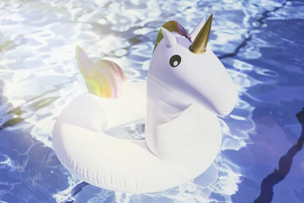 Unicornio blanco colorido inflable en la piscina. Tiempo de vacaciones en la piscina con juguetes de plástico. Concepto de relajación. Ripple Agua en piscina con reflejo solar.Sunlights efectos . — Foto de Stock