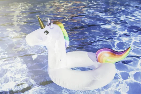 Unicornio blanco colorido inflable en la piscina. Tiempo de vacaciones en la piscina con juguetes de plástico. Concepto de relajación. Ripple Agua en piscina con reflejo solar.Sunlights efectos . — Foto de Stock