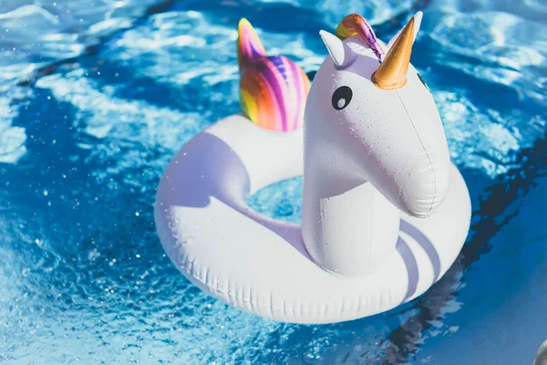 Надувний барвистий білий єдиноріг у басейні. Час відпустки в басейні з пластиковими іграшками. . — стокове фото