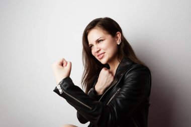Moda fotoğraf güzel bir esmer kadının beyaz boş arka plan üzerinde poz karanlık uzun saçlı deri ceket giyiyor. Olumlu insan duyguları, tepki, jestler. Moda kadın kavramı.