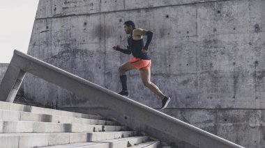 Bir merdivenin Koşu hızı ile eğitim veya basamaklardan koşu sırasında açık havada çalışma siyah tişört sportif genç adam kas İspanyol Genç erkek esmer atlet