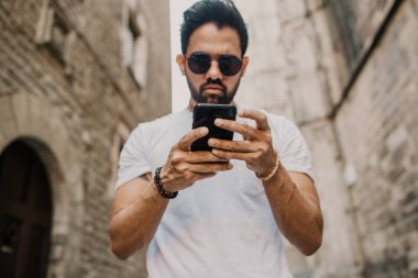 Akıllı telefon kullanan genç kentsel profesyonel adam. Yenilikçi iş arkadaşınız hareket eden smartphone güneş gözlüğü takıyor app mesaj sms mesajı kullanarak holding