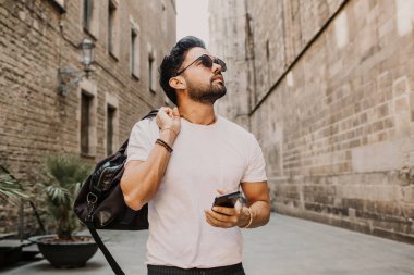 Akıllı telefon kullanan genç kentsel profesyonel adam. Yenilikçi iş arkadaşınız hareket eden smartphone güneş gözlüğü takıyor app mesaj sms mesajı kullanarak holding