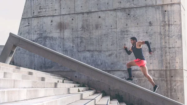 Muscular hispano de piel oscura atleta masculino construir corriendo un tramo de escaleras con speed.Concret pared de fondo con área de espacio de copia para mensajes de texto o contenido publicitario . —  Fotos de Stock