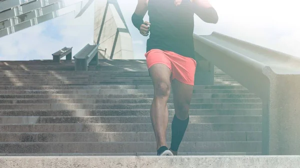 Musculoso hispano Joven atleta de piel oscura corriendo por un tramo de escaleras con velocidad, joven deportivo en entrenamiento de camiseta negra o haciendo ejercicio al aire libre mientras trota por los escalones. Ancho.Cultivado . —  Fotos de Stock