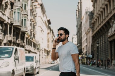 Akıllı telefon kullanan genç kentsel profesyonel adam. Yenilikçi iş arkadaşınız hareket eden smartphone güneş gözlüğü takıyor app mesaj sms mesajı kullanarak holding