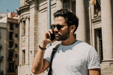 Yakışıklı sakallı İspanyol adam için dalga köpüğü hareket eden smartphone kullanarak Internet, web yapma çağrısı ve seyir dijital şehir haritası. Seyahat elektronik cihaz kullanarak erkek