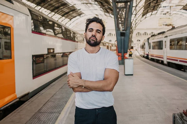 Счастливый мужчина в белой футболке ждет поезда на вокзале . — стоковое фото