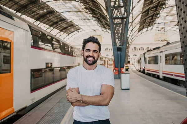 Happy Traveler male discover a big europe city, travel and active lifestyle concept.Bearded hispanic Tourist Man in white tshirt waiting his train on railway station.
