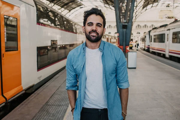 Happy Traveler male discover a big europe city, travel and active lifestyle concept.Bearded hispanic Tourist Man in blue shirt waiting his train on railway station.