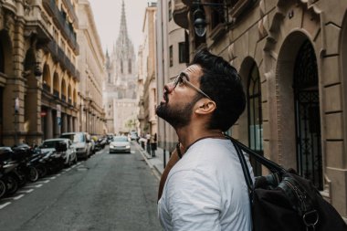 Gezgin erkek keşfetmek bir büyük Avrupa şehir, seyahat ve aktif yaşam tarzı kavramı. Sakallı turist adam siyah deri bir çanta güzel şehir seyahat keyfini çıkarın. Kırpılmış.
