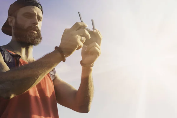 El modelo masculino barbudo utiliza el control remoto del dron para volar el dispositivo en el aire. Hombre operando drones volando en la naturaleza. Concepto de nuevas tecnologías e innovaciones . —  Fotos de Stock