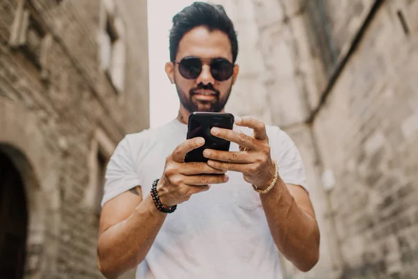 Unga urbana manliga professional med smart telefon. Hipster medarbetare håller mobil smartphone med appen sms sms-meddelande som bär solglasögon — Stockfoto