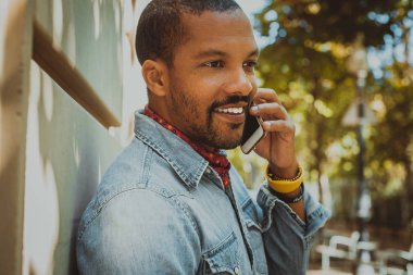 Amerikan Afrika erkek hipster güneşli gün boyunca cep telefonu kullanarak.