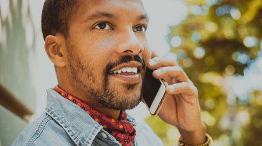 Amerikan Afrika erkek hipster güneşli gün boyunca cep telefonu kullanarak.