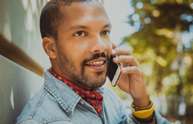 Amerikan Afrika erkek hipster güneşli gün boyunca cep telefonu kullanarak.