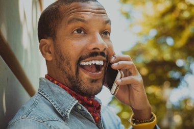 Amerikan Afrika erkek hipster güneşli gün boyunca cep telefonu kullanarak.