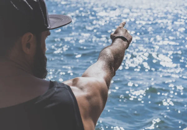 Retrato del hombre barbudo reflexivo apuntando mano masculina a la orilla del mar y mirando a la distancia en el horizonte en el mar. Primer plano. . —  Fotos de Stock