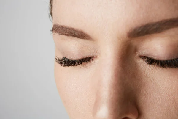Close-up retrato Beleza mulheres com grandes olhos fechados e olhos escuros.Modelo com maquiagem nua luz, fundo estúdio cinza . — Fotografia de Stock