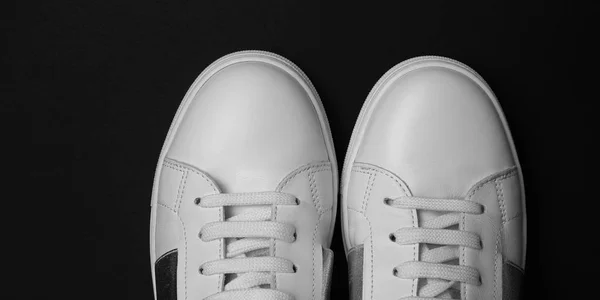 Накладні фото жіночих білих кросівок на чорному тлі. Широкий . — стокове фото