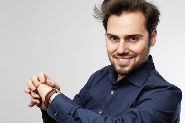 Gülümseyen ve saatini arayan bir işadamı. Gri bir arka plan üzerinde izole