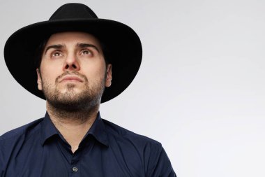 Emin yakışıklı İspanyol adam beyaz arka plan üzerinde giyen siyah şapka ararken izole.