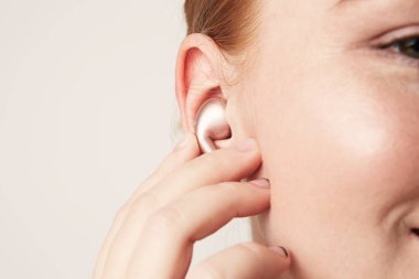 Yakın çekim portre sevimli Kızıl saçlı beyaz kadın ile mutlu gülümseme kulakta kablosuz kulaklık ile müzik dinleme.