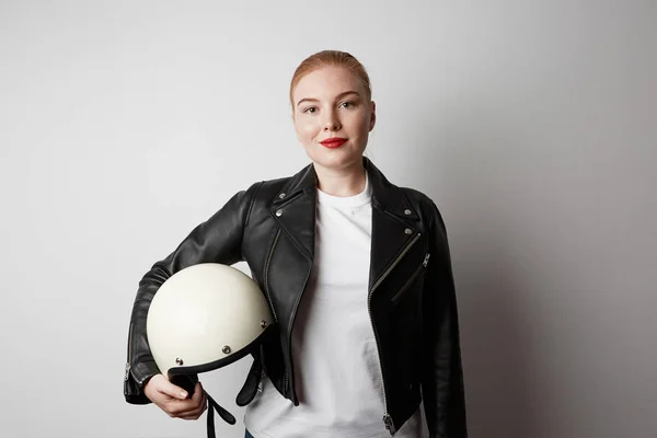 Handsome woman wearing black leather jacket and holding moto helmet smiling on white background. Fashion, glamour and moto wear concept. — Stock Photo, Image