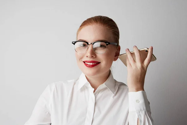 Beautiful redhead woman using mobile phone at office over gray background. — Stock Photo, Image