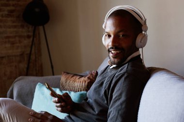 Afrika kökenli Amerikalı adam yaptığı telefon müzik dinlerken kulaklık ile gülümseyen. Gevşeme kavramı.