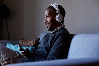 Telefonuna müzik dinlerken kulaklık ile çekici bir Afro-Amerikan adam. Gevşeme kavramı.
