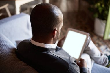 Afrika siyah adam evde oturma odasında kanepe kanepede tablet kullanma.