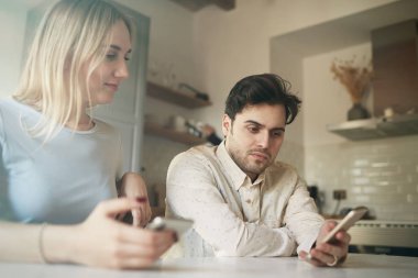 Çekici Hispanik erkek ve sarışın kadın evde cep telefonunu kullanarak.