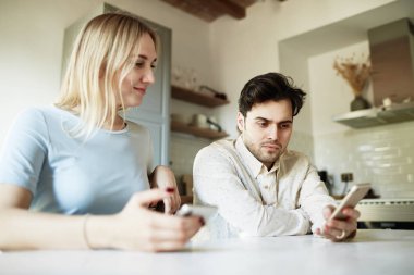 Çekici Hispanik erkek ve sarışın kadın evde cep telefonunu kullanarak.