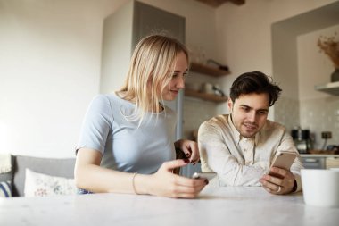 Çekici Hispanik erkek ve sarışın kadın evde cep telefonunu kullanarak.