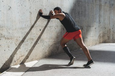 Erkek koşucu germe egzersiz yapmak için sabah idmanları açık hazırlanıyor.
