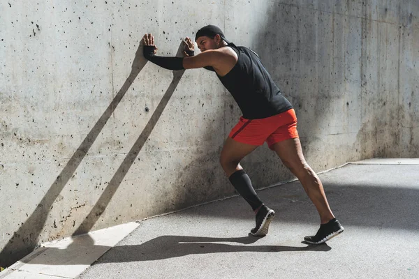 Corredor masculino haciendo ejercicio de estiramiento, preparándose para el entrenamiento matutino al aire libre . —  Fotos de Stock