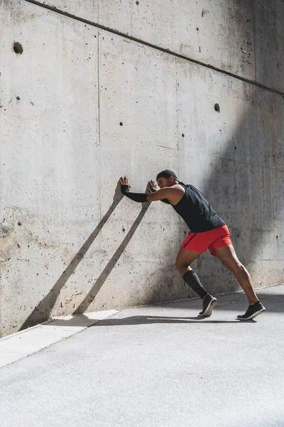 Corredor masculino haciendo ejercicio de estiramiento, preparándose para el entrenamiento matutino al aire libre. Vertical —  Fotos de Stock