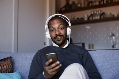 Çekici Afro-Amerikan erkek beyaz kulaklık müzik yaptığı telefon ile. Gevşeme kavramı.