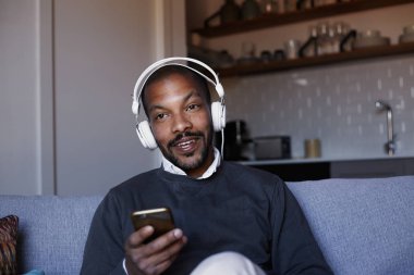 Çekici Afro-Amerikan erkek beyaz kulaklık müzik yaptığı telefon ile. Gevşeme kavramı.