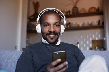 Çekici Afro-Amerikan erkek beyaz kulaklık müzik yaptığı telefon ile. Gevşeme kavramı.