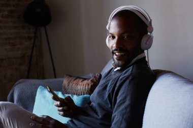 Çekici Afro-Amerikan erkek beyaz kulaklık müzik yaptığı telefon ile. Gevşeme kavramı.