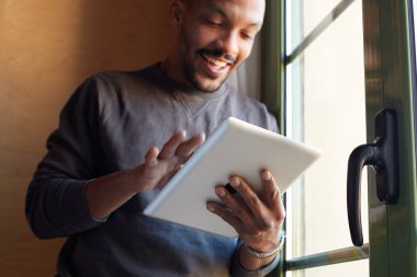 Gülümseyen Afrika siyah adam ev salon tablet kullanma.