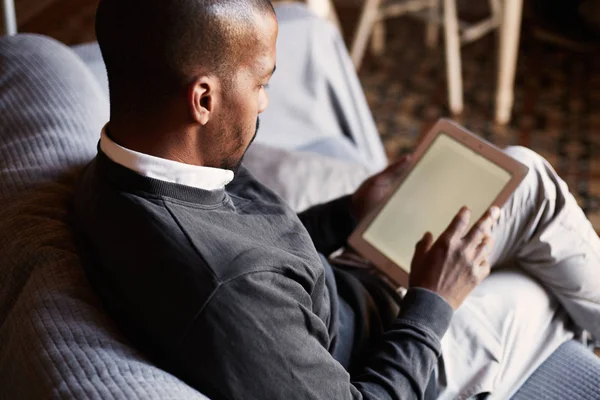 Zarif Afrika siyah adam evde oturma odasında kanepe kanepede tablet kullanma.
