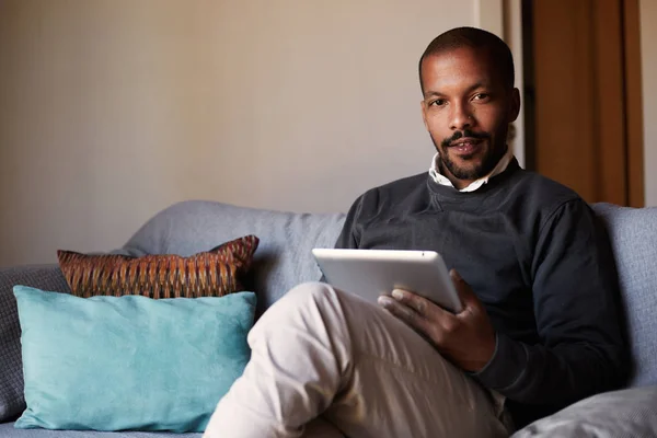 Bonito homem negro africano usando tablet no sofá na sala de estar em casa . — Fotografia de Stock